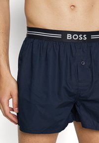 Boxers bleu marine en tissu lisse et léger. Dotés d'une taille élastique confortable avec le logo "BOSS" et un bouton à l'avant.