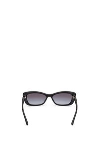Gafas de sol negras con montura redondeada, lentes degradados y brazos de patilla delgados. Presentan un sutil logo en los lentes.