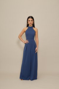 Ναυτικό μπλε ολόσωμη φόρμα με λαιμόκοψη halter, εφαρμοστή μπούστα και παντελόνια φαρδιάς γραμμής. Λείο ύφασμα, πιετέ λεπτομέρειες και μίνιμαλ στοιχεία σχεδιασμού.