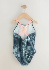 Kaksiosainen uimapuku, laivastonsininen tie-dye-kuvio, X-mallinen selkäosa korallinvärisillä hihnoilla, pehmeää kangasta ja korkeat lahkeensuut. Roikkuu puuhakassa.