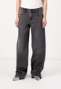 Jeans en denim noir à taille haute et jambes larges, avec une texture délavée, comprenant des poches avant, des passants de ceinture et des détails de couture subtils.