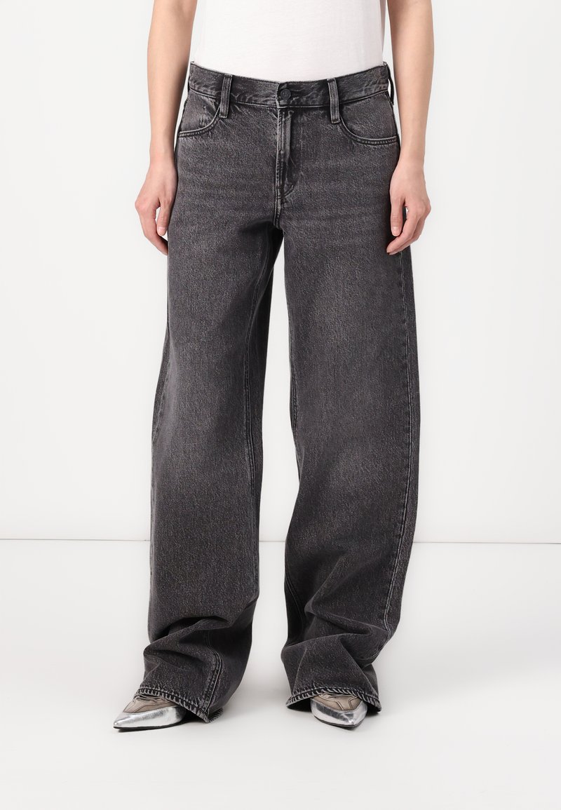 Jeans en denim noir à taille haute et jambes larges, avec une texture délavée, comprenant des poches avant, des passants de ceinture et des détails de couture subtils.