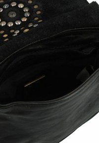 Borsa a tracolla in pelle nera con superficie testurizzata, caratterizzata da borchie metalliche disposte in motivi circolari. L'interno ha una fodera in tessuto e una piccola tasca.