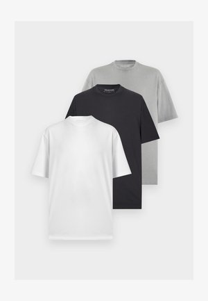Trois t-shirts à manches courtes à col rond unis en blanc, noir et gris, présentés superposés sur un fond clair.