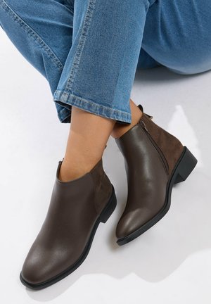 Botas de tobillo de cuero marrón con un acabado suave, paneles de ante en contraste y un tacón bajo. Detalle de cremallera lateral para facilitar su uso.