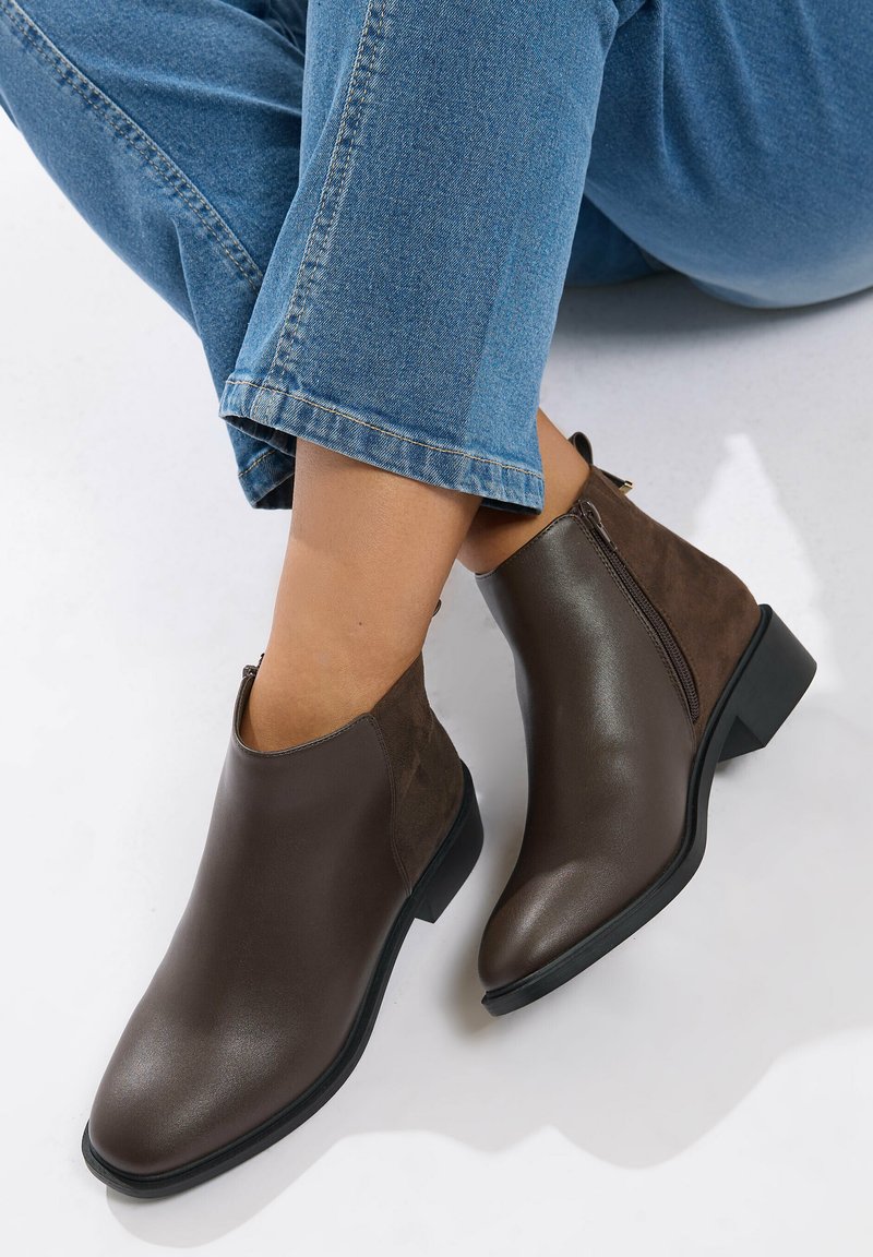 Bruna läderankelstövlar med en slät yta, kontrasterande mockadetaljer och en låg klack. Sidoblixtlås för enkel påtagning.