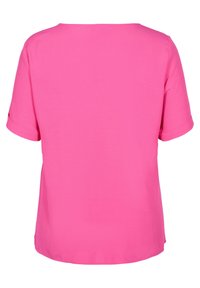 Top rosa a maniche corte con vestibilità ampia, scollatura rotonda e polsini arrotolati. Tessuto liscio di un solo colore, senza motivi o decorazioni visibili.