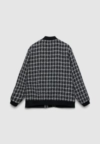 Blouson aviateur à carreaux noir et blanc avec col et poignets en maille, présentant un tissu texturé et une coupe droite.