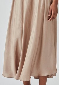 Beige satin midi-skirt med et flydende design, der har en glat tekstur, blød fald og en cirkulær kant, der giver en blid silhuet.