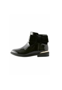 Schwarze Lackstiefelette mit rundem Zehenbereich, samtigem Schleifendetail an der Seite und einer kleinen goldenen Akzentuierung an der Ferse. Insgesamt glatte Textur.