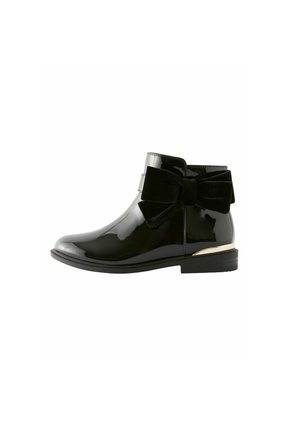 Schwarze Lackstiefelette mit rundem Zehenbereich, samtigem Schleifendetail an der Seite und einer kleinen goldenen Akzentuierung an der Ferse. Insgesamt glatte Textur.