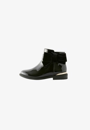 Bottines en patent noir avec un bout arrondi, détail en velours sur le côté, et un petit accent doré sur le talon. Texture lisse dans l'ensemble.