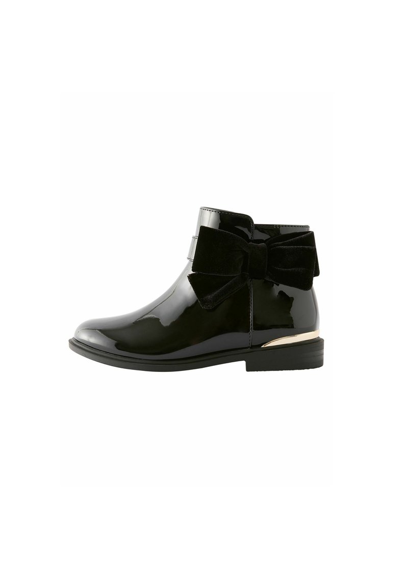 Schwarze Lackstiefelette mit rundem Zehenbereich, samtigem Schleifendetail an der Seite und einer kleinen goldenen Akzentuierung an der Ferse. Insgesamt glatte Textur.