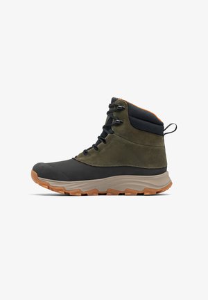 Scarponcino da trekking alto con punta in gomma nera, parte superiore in suede oliva, colletto in tessuto nero e suola in gomma tan con battistrada testurizzato.