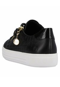 Czarne sneakersy z plecionym wzorem, błyszczącymi akcentami i złotą zawieszką. Biała podeszwa z fakturowaną powierzchnią dla lepszej przyczepności.