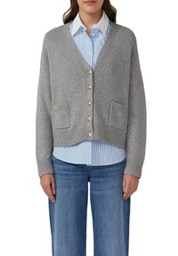 Grauer gestrickter Cardigan mit V-Ausschnitt, goldenen Knöpfen und zwei aufgesetzten Taschen, über einem hellblauen gestreiften Hemd getragen. Klassischer und lässiger Schnitt.