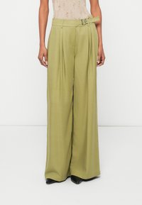 Πλατιά παντελόνια σε ελιά πράσινο ύφασμα με πιέτες, ζώνη με ασημένια αγκράφα και λεία υφή. Φοριέται με μαύρες γόβες.