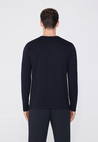 Marineblaue Langarmshirt aus einem glatten Stoff. Mit Rundhalsausschnitt und enganliegenden Bündchen. Minimalistisches Design ohne sichtbare Muster oder Akzente.