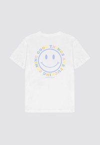 Biela bavlnená tričko s okrúhlym grafickým dizajnom na zadnej strane. Dizajn obsahuje úsmevný tvár a farebný text, "DOBRÉ VECI PRICHÁDZAJÚ."