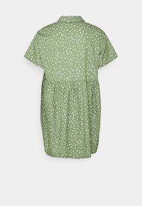 Robe vert clair à manches courtes avec petit imprimé floral blanc, col et taille froncée, vue de dos sur un fond uni.