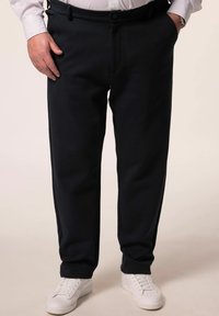 Marinehosen aus einem weichen, strukturierten Stoff bieten einen flachen Sitz, Seitentaschen und einen Knopfverschluss und werden mit weißen Sneakers kombiniert.