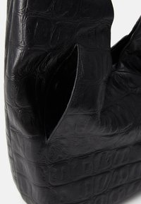 Bolso de piel negra con un patrón texturizado de piel de cocodrilo. Diseñado con dos asas recortadas y una forma estructurada y angular.