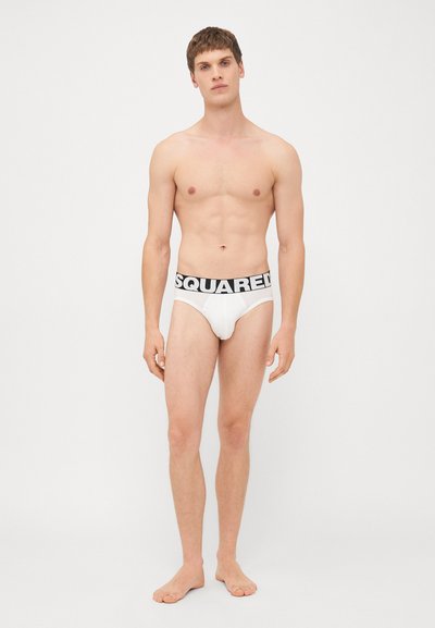 Caleçons blancs pour hommes avec une ceinture noire portant l'inscription "SQUARED" en lettres majuscules. Le tissu semble lisse et extensible.