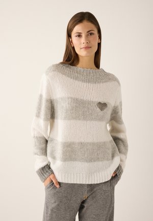 Striped pullover sweater in white and gray, featuring a heart detail on the chest, ribbed neckline, and cuffs. Soft, textured knit fabric.