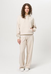 Beige hoodie met een voorzak en een losse pasvorm, gecombineerd met bijpassende beige sweatpants. Beide gemaakt van zachte, gestructureerde stof.