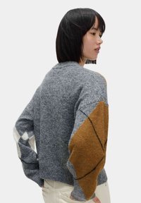 Gestreifter Pullover mit geometrischem Muster in Grau, Braun und Weiß. Lockere Passform mit weiten Ärmeln und kurzer Länge.