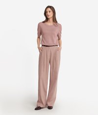 Ljusrosa kortärmad tröja i kombination med löst sittande, högmidjade beige byxor. Båda plaggen har släta texturer.