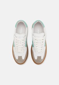 White sneakers with light blue accents, gray suede detailing, and brown rubber soles; featuring lace-up design and padded tongue.