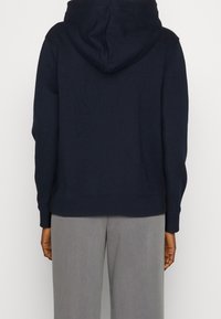 Felpa blu navy con tasca a marsupio, polsini e orlo a costine, realizzata in materiale morbido. Presenta un cappuccio con coulisse e una superficie liscia.