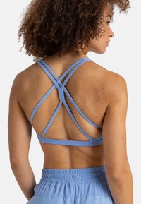 Sujetador deportivo azul claro con tirantes cruzados en la espalda, hecho de un material liso y elástico. Destacado por una banda elástica ancha.