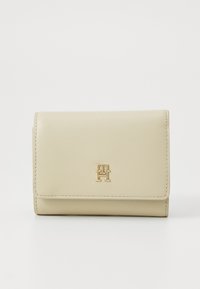 Beige nahkajalusta, jossa on teksturoitu pinta, kultainen logo ja siisti ommel reunoilla. Käännettävä malli suorakulmaisen muotoinen.