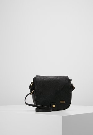 Sac bandoulière en cuir noir avec motif floral embossé, quincaillerie dorée et fermeture à rabat avant sur socle d'exposition blanc.