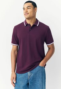 Polo in bordeaux con dettagli bianchi su colletto e maniche. Realizzato in tessuto morbido, presenta una chiusura a bottoni e una vestibilità comoda.