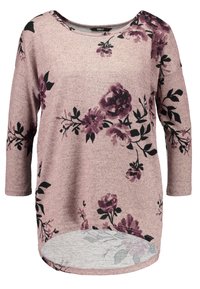 Haut à manches longues en tissu rose doux avec un motif floral en violet foncé et noir. L'ourlet arrondi et l'encolure en scoop viennent embellir le design.