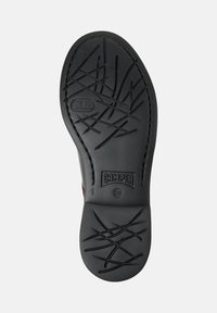 Semelle de chaussure noire avec des motifs de criblage abstraits en croix, logo de la marque Camper, taille 38, et un petit emblème rectangulaire près du talon.