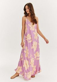 Maxi šaty z lehkého fialového materiálu s velkými béžovými květinovými vzory, na tenkých ramínkách a s volným střihem. Hladká textura, délka po kotníky.