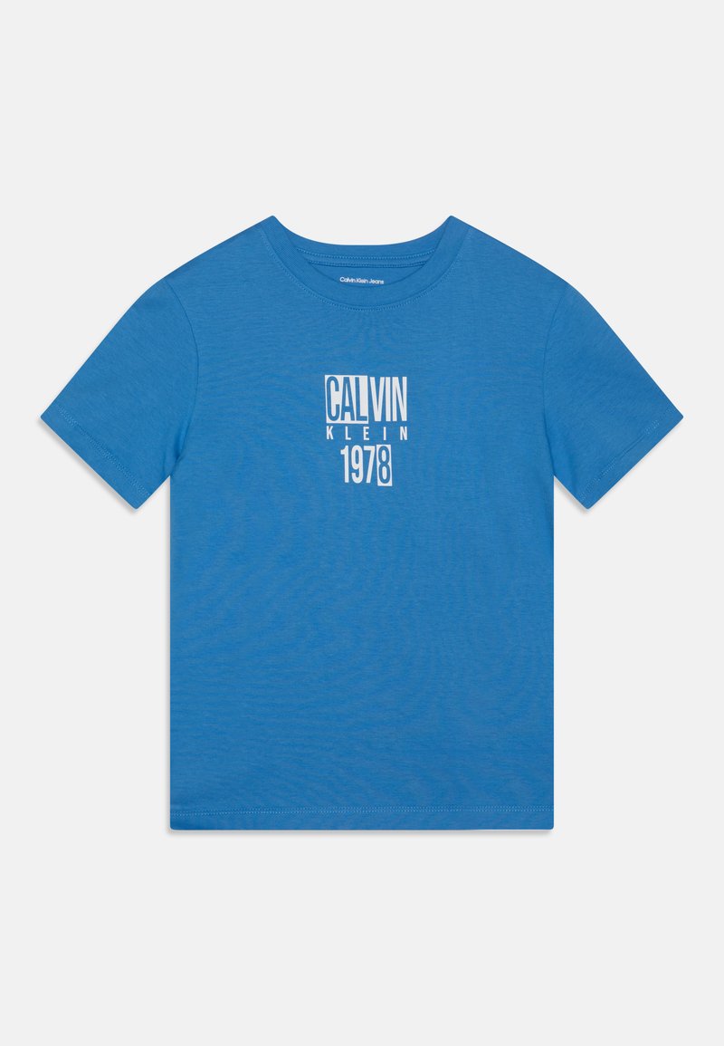 Camiseta de algodón azul con cuello redondo, mangas cortas y un estampado gráfico que dice "CALVIN KLEIN 1978" en blanco, centrado en el frontal.