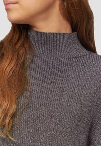 Pull à col roulé côtelé gris foncé avec une finition texturée. Il présente une coupe ajustée et un léger éclat grâce aux fils métalliques tissés.