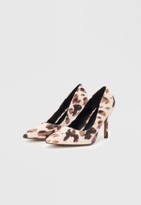 Des chaussures à talons hauts en imprimé léopard avec un bout pointu, un tissu doux et une fine chaussure à talon aiguille. La palette de couleurs comprend du beige et du marron foncé.