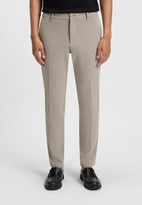 Beżowe dopasowane spodnie wykonane z gładkiego materiału o smukłym kroju, z zapięciem na guzik, bocznymi kieszeniami i bez widocznych wzorów.