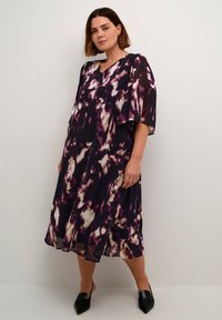 Robe fluide en tissu léger, avec une base violet foncé ornée de motifs abstraits crème et violet clair, et des manches larges.