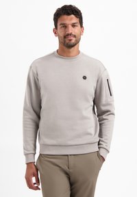 Hellgraues Sweatshirt mit Rundhalsausschnitt, gerippten B ündchen und Saum. Mit einem schwarzen sechseckigen Logo und einer Reißverschlusstasche am Ärmel.