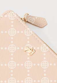 Καφετί υφασμάτινο πορτοφόλι με άσπρο κυκλικό και πουά σχέδιο, χρυσό φερμουάρ και μικρό χρυσό λογότυπο "AH" στο μπροστινό μέρος.