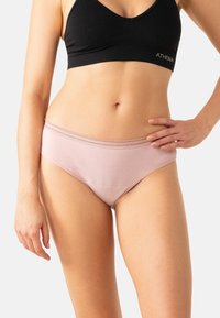 Culotte en coton rose clair avec une texture lisse et des coutures décoratives le long de la ceinture, associée à un crop top noir.