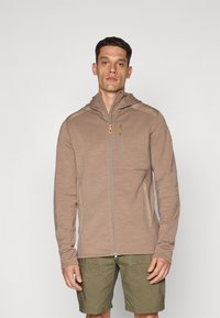 Giacca cappotto zip-up color marrone chiaro con cappuccio, caratterizzata da accenti beige sulle spalle e due tasche frontali. Realizzata in un materiale texture.
