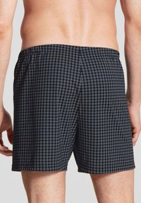 Shorts de bain navy avec un motif géométrique blanc, taille élastique et coupe décontractée. Fabriqués en tissu léger et à séchage rapide.